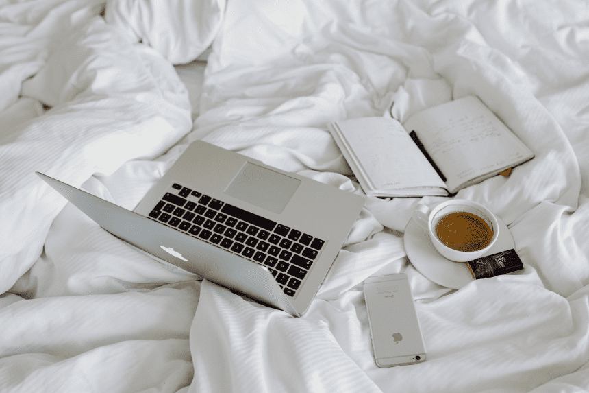a laptop and a journal in bed