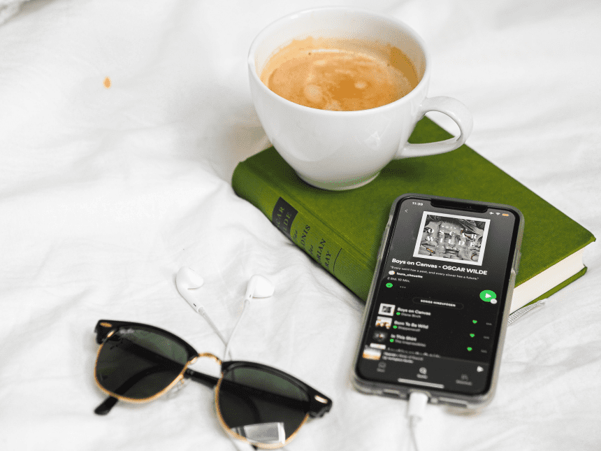 a cup of coffee, a book and a phone with a playlist